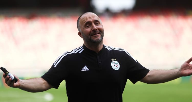 Belmadi souriant avec un micro en main sur le terrain.