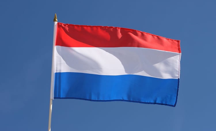 Drapeau des Pays-Bas flottant dans le ciel bleu clair.