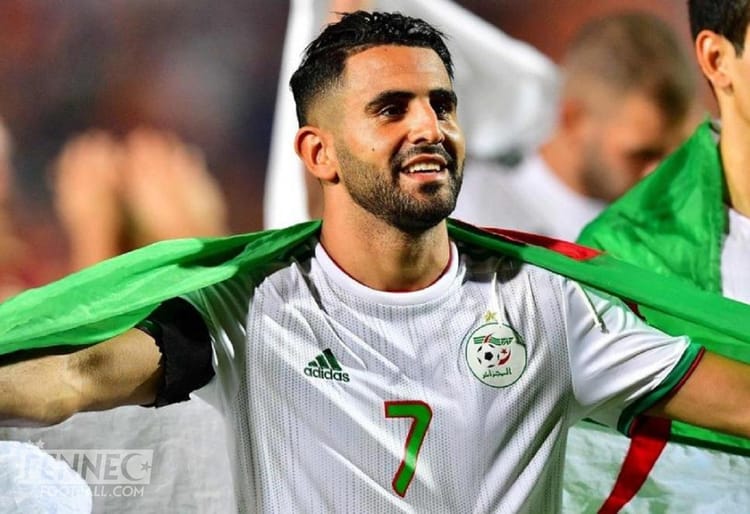 Riyad Mahrez en tenue de football avec drapeau algérien.