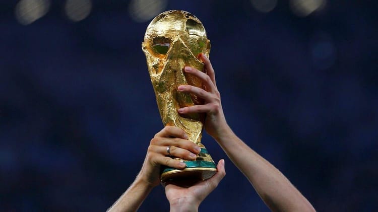 Main tenant la coupe du monde en or lors d'une cérémonie.