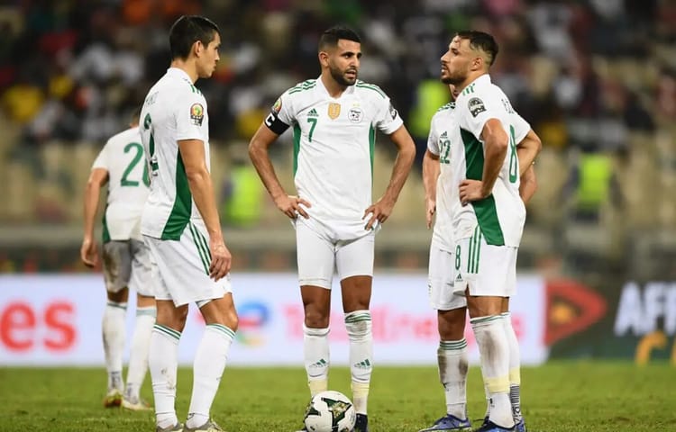 Joueurs de football algériens en discussion sur le terrain.