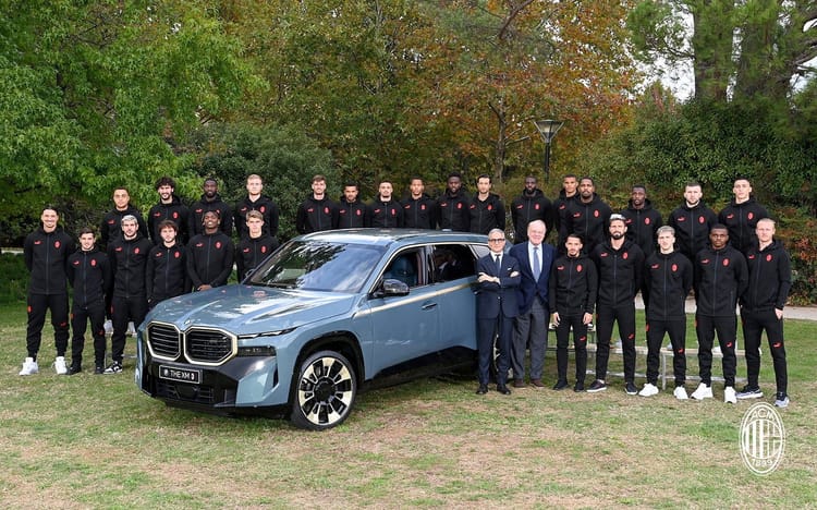 Découvrez la nouvelle voiture d'Ismael Bennacer L'équipe d'Ismael Bennacer posant avec une voiture moderne en plein air.