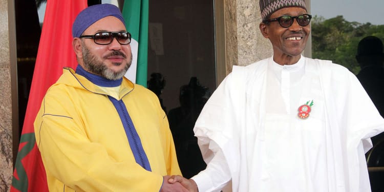 Deux hommes en tenue traditionnelle se serrent la main lors d'une rencontre officielle.