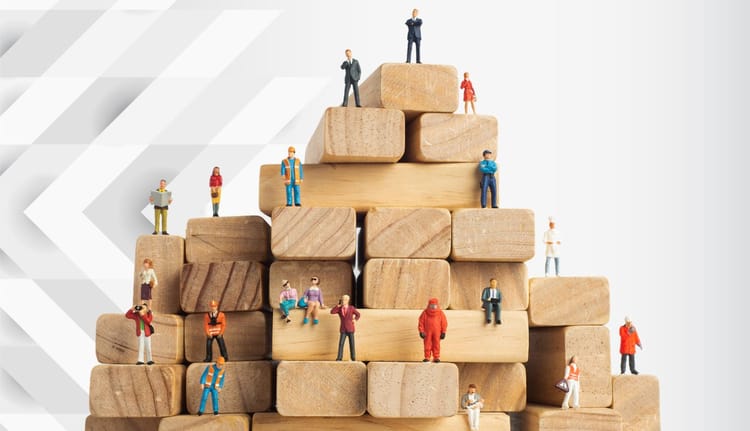 Figurines miniatures sur blocs en bois symbolisant la collaboration et la croissance.