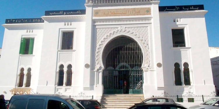 Palais de justice blanc avec grande porte en fer forgé et architecture marocaine.