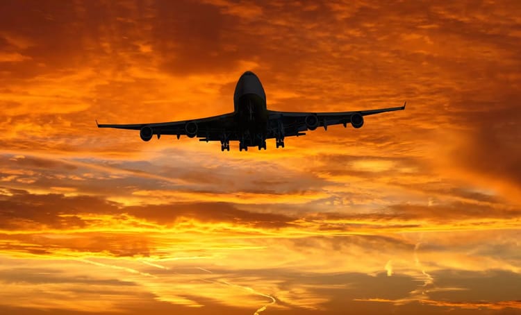 Avion survole le ciel au coucher du soleil avec des couleurs orange et dorées.