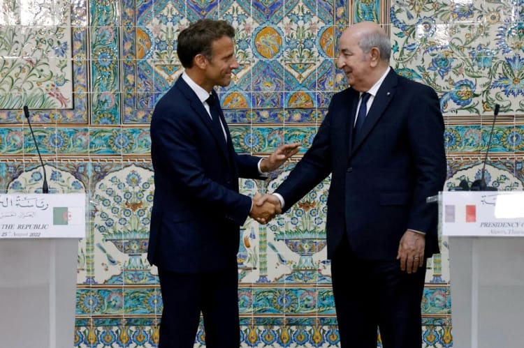 Deux hommes en costume se serrent la main devant un décor marocain traditionnel.