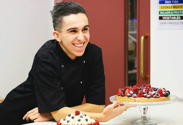Hadj Mebarek souriant avec un gâteau aux fruits et baies.