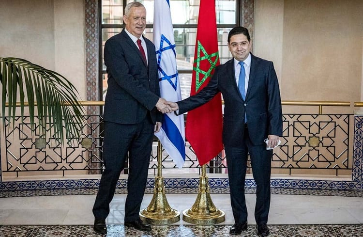 Ces hommes de main d'Israël qui réclament une guerre entre l'Algérie et le Maroc. Deux hommes d'État se serrent la main devant les drapeaux d'Israël et du Maroc.