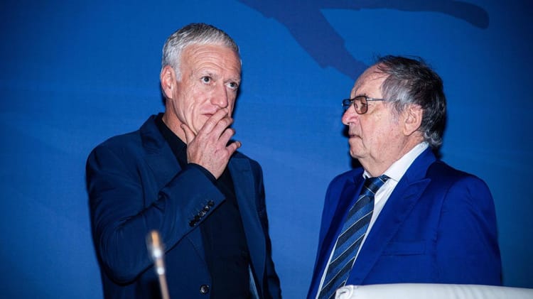 Didier Deschamps et un autre homme en conversation lors d'un événement.