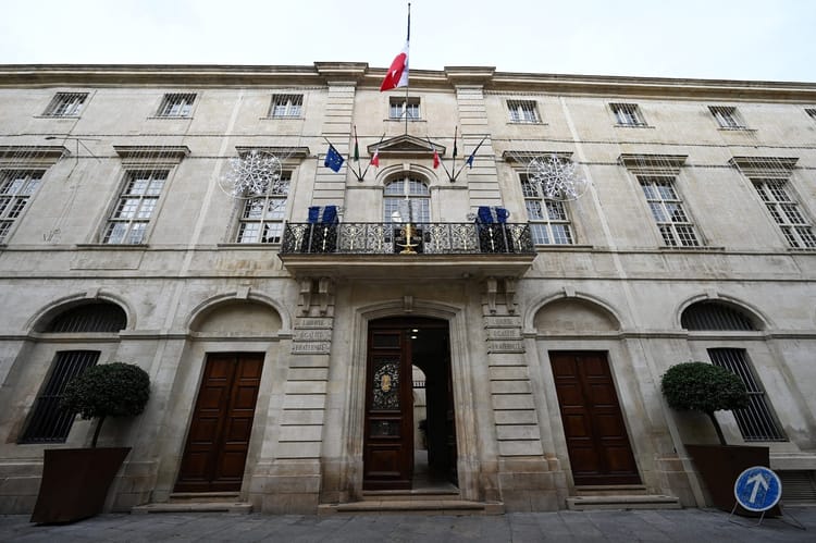 Façade d'un bâtiment officiel avec drapeaux français et européens.