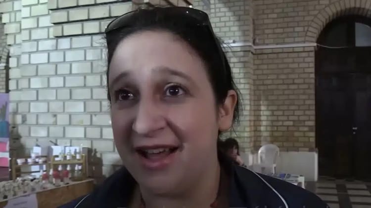 Femme jeune parlant kabyle, expression enthousiaste, arrière-plan en briques.