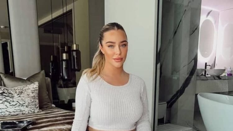 Taylor Ward posant dans une pièce élégante, vêtue d'un pull blanc.