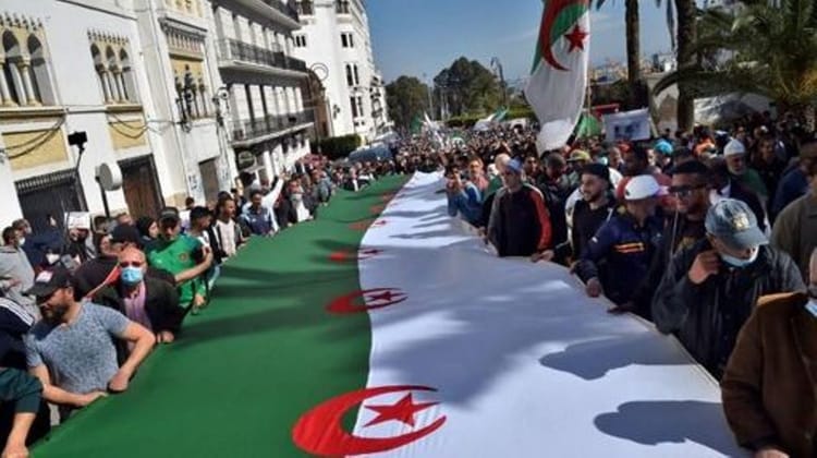 Manifestation en Algérie avec un grand drapeau national algérien.