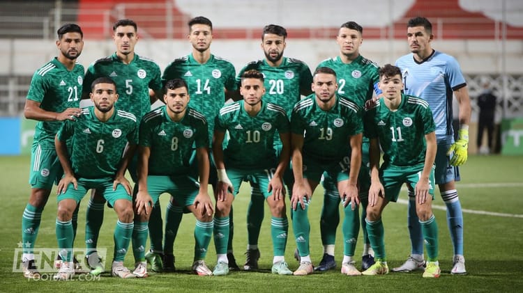 Groupe de joueurs de football algériens en uniforme vert sur le terrain.
