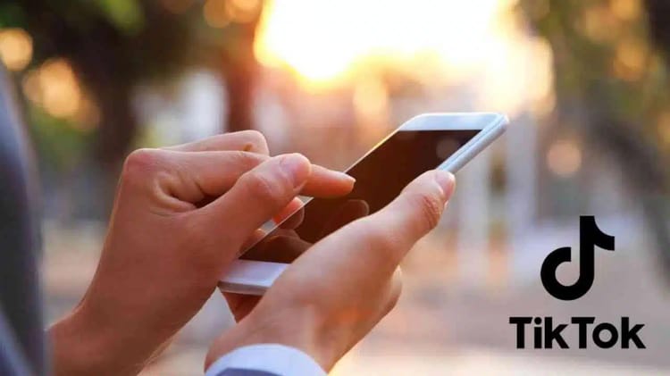Personne utilisant un smartphone pour créer une vidéo TikTok en extérieur.