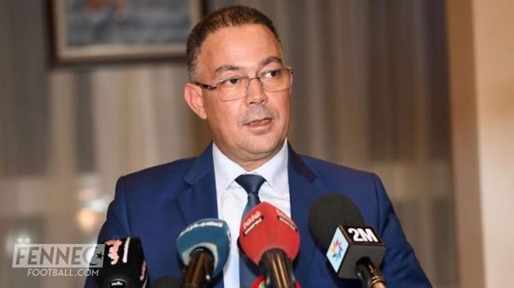 Homme en costume parlant lors d'une conférence de presse sportive au Maroc.