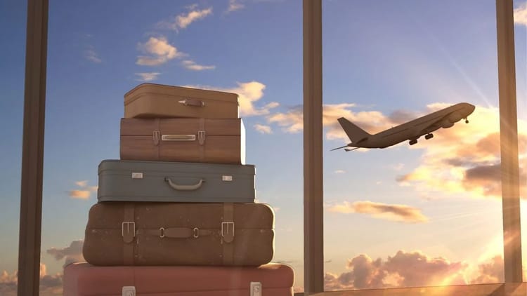 Destinations tendances en 2023 : l’Algérie y figure? La réponse... Valises empilées près d'une fenêtre avec avion en vol au coucher du soleil.