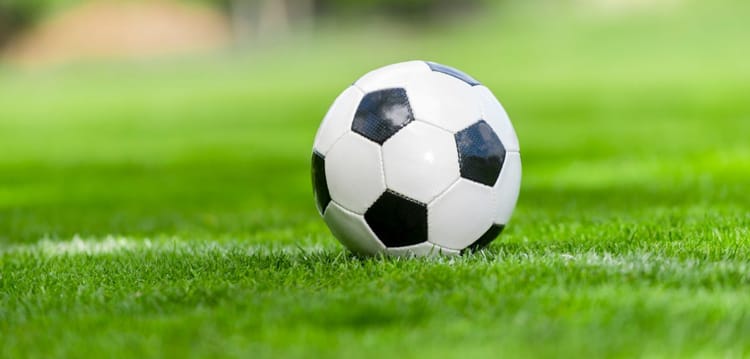 Monde du football : Zoom sur quelques cas de situations injustes Ballon de football sur le terrain vert en plein air.