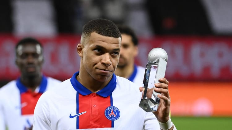 Kylian Mbappé tenant un trophée lors d'une cérémonie de remise de prix.