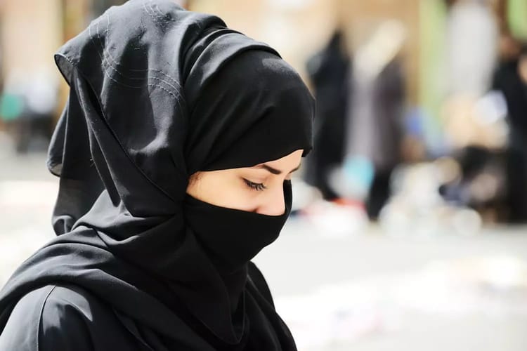 Jeune femme portant un hijab noir dans un espace public.