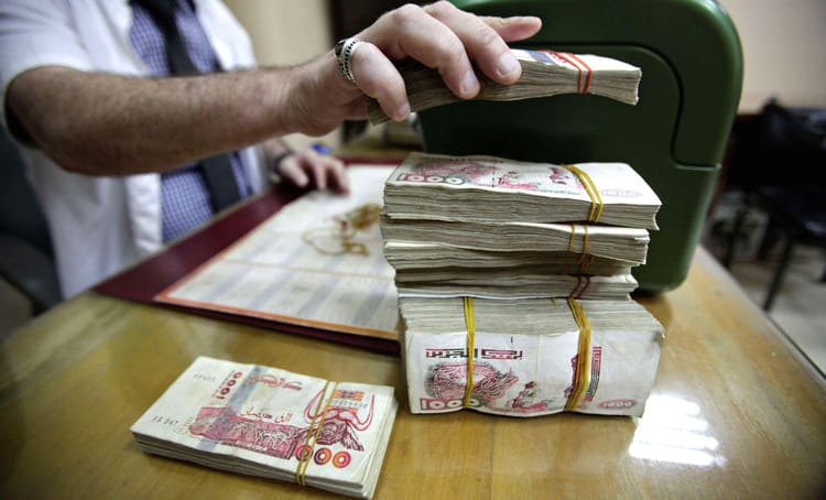 Intégration de l’argent du marché noir dans les circuits bancaires : Tebboune resserre les mailles Stacks de billets de banque en dinar algérien sur une table.