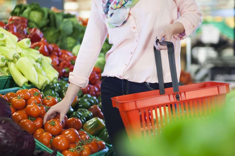 Femme achetant des tomates dans un marché coloré en Algérie.