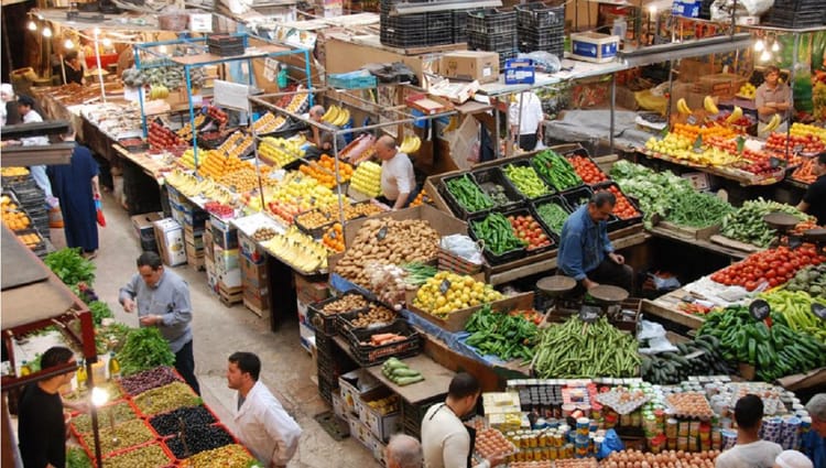 Vendeurs et clients dans un marché coloré en Algérie.