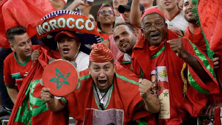 Supporters marocains en fête pour la CAN 2025, portant des drapeaux et accessoires marocains.