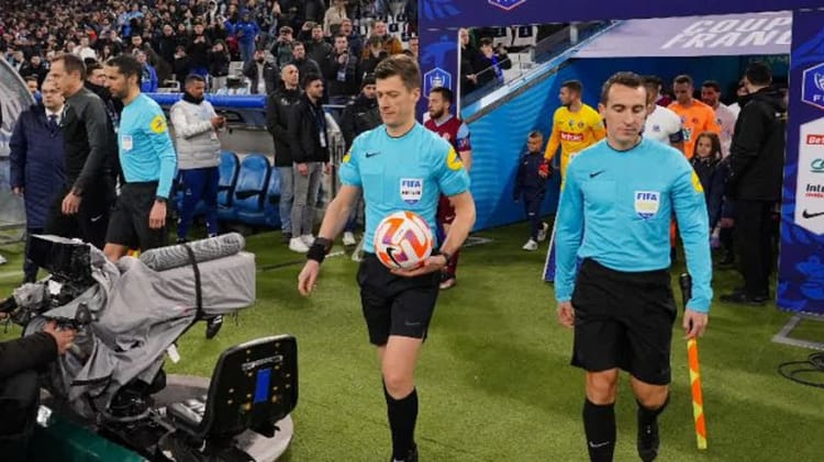 Arbitres en tenue bleue sur le terrain de football avant un match.