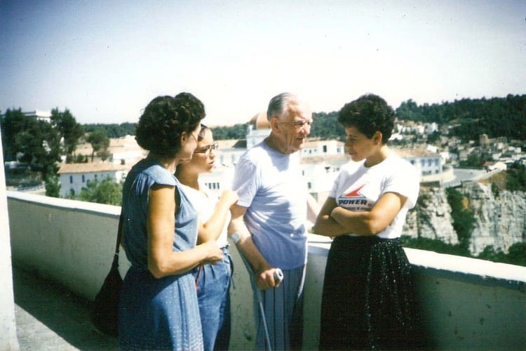 Groupe de quatre personnes discutant sur un balcon avec vue sur la ville.