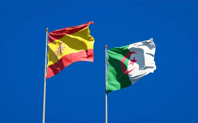 Drapeaux de l'Espagne et de l'Algérie flottant dans le ciel bleu.