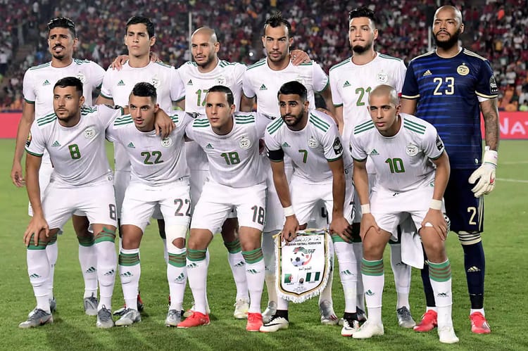 Groupe de joueurs algériens en tenue de match sur le terrain.