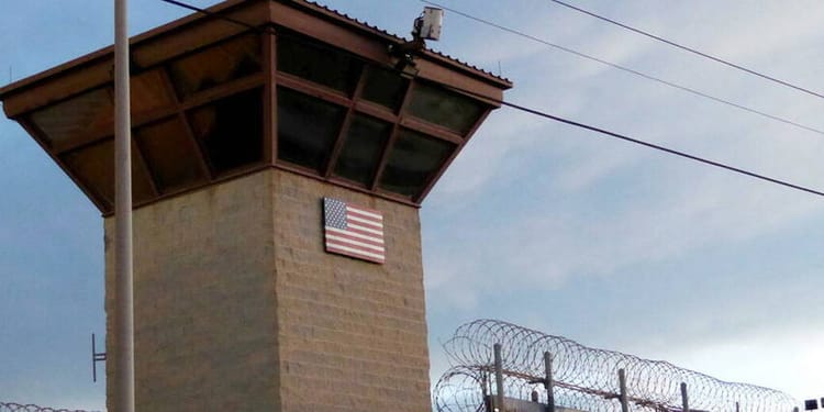 USA : un Algérien retrouve la liberté après 20 ans de détention Tour de garde avec drapeau américain et barbelés.