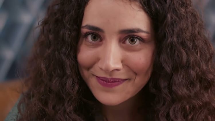 Femme aux cheveux bouclés et regard expressif, sourire doux.