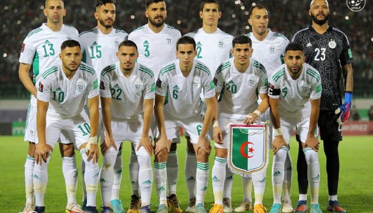 Groupe de joueurs de football algériens en uniforme blanc sur le terrain.