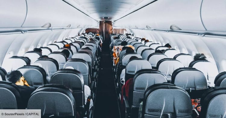 Cabine d'avion avec passagers assis, vue centrale.