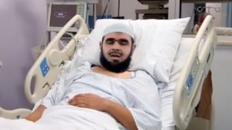Imam Mahsas allongé dans un lit d'hôpital avec un bandage sur la tête.