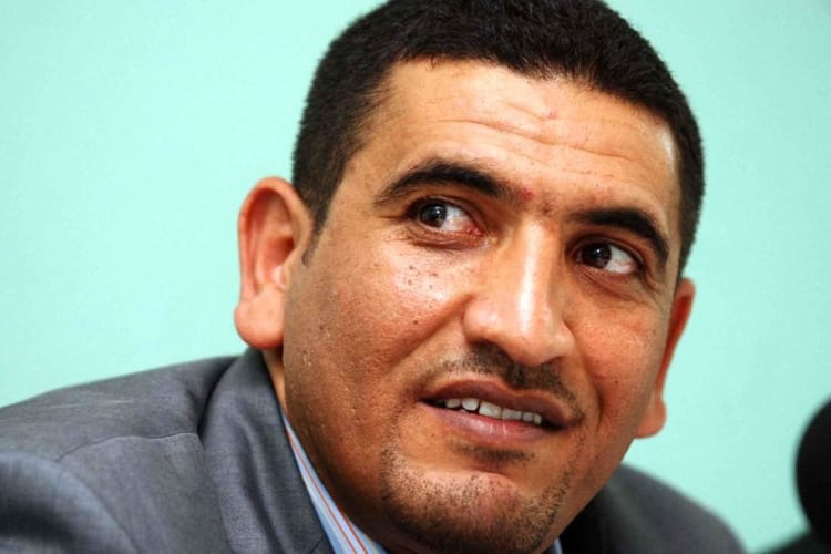 Karim Tabbou lors d'une conférence à Alger, visage sérieux.