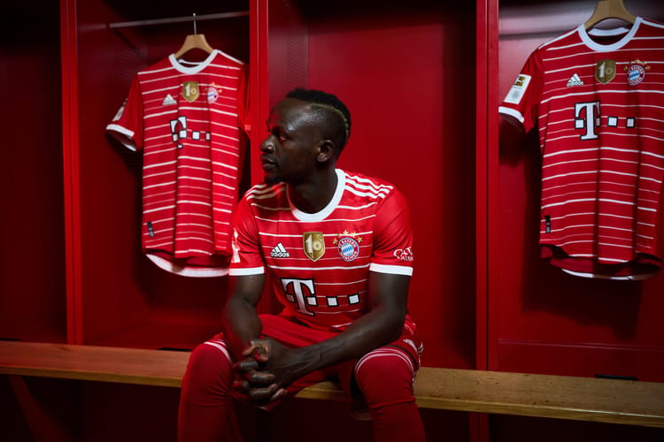 Joueur du Bayern Munich dans le vestiaire avec maillot rouge.