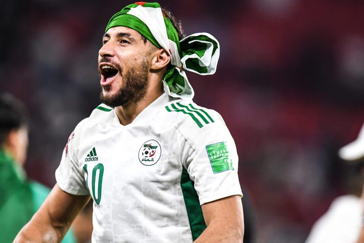 Youcef Belaïli en maillot de l'équipe nationale algérienne, célébrant une victoire.