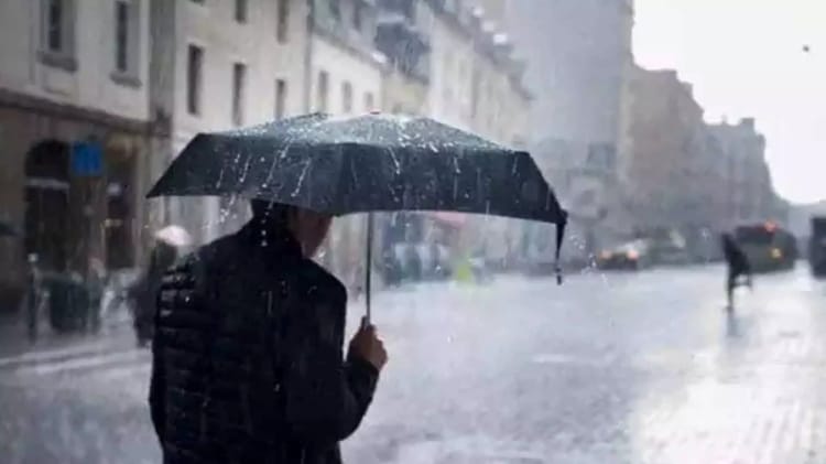 Personne avec parapluie sous forte pluie en ville.