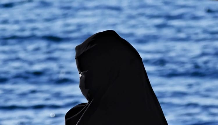 Femme portant un jilbab noir près de l'eau.