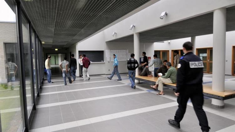 Policiers et personnes dans un hall d'entrée en France.