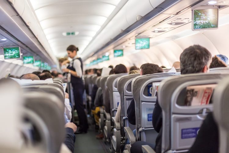 Cabine d'avion Air Algérie avec passagers et écrans de divertissement.