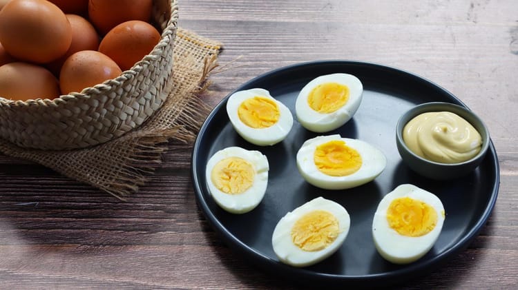 Œufs durs coupés en moitiés avec sauce dans une assiette noire.
