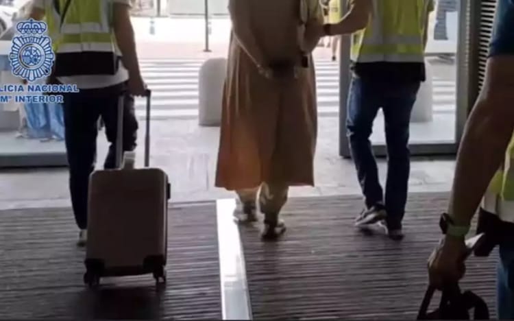 Espagne : une Marocaine abandonne son enfant dans un aéroport (Quel genre de mère ?) Personne en hijab avec valise à l'aéroport, entourée de personnel de sécurité.