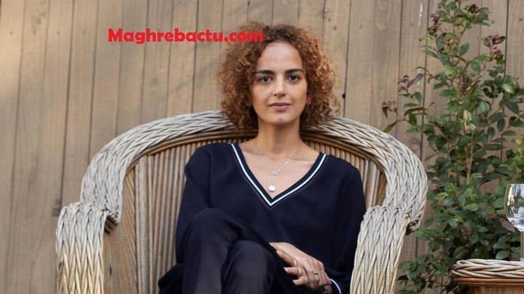 Femme avec cheveux bouclés assise dans un fauteuil en bois.