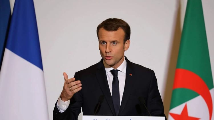 Emmanuel Macron parlant lors d'une conférence officielle avec drapeaux algérien et français.