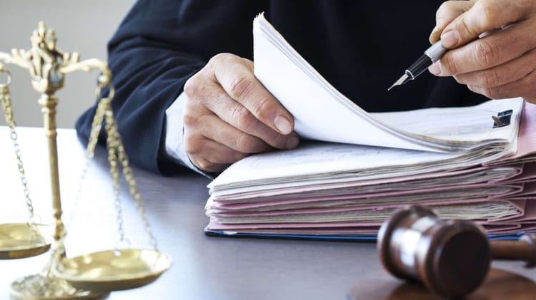 Personne en costume avec documents et balance de justice.